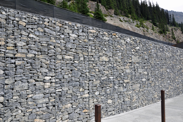 the netted rock wall with the highway above